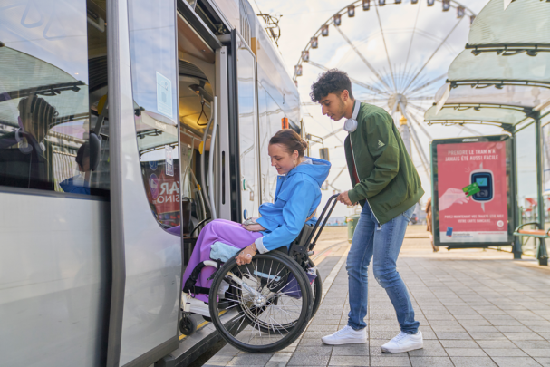 Jongen helpt meisje in rolstoel in de tram.